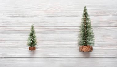 Minimalist Noel Dekoru Beyaz Ahşap Arkaplanda İki Minyatür Noel Ağaçları