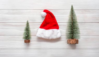 Miniature Christmas Trees with Santa Hat on White Wooden Background for Festive Decor clipart