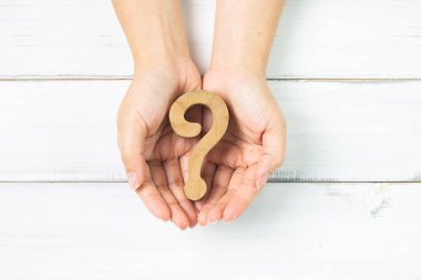 Nurtured Curiosity: Hands Gently Holding a Wooden Question Mark clipart