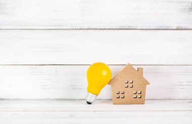 Ev için Parlak Fikirler: Kırsal Beyaz Arkaplan Üzerine Sarı Ampul ve Ahşap Ev Modeli
