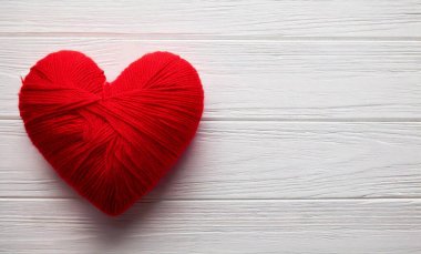 Beyaz Ahşap Arkaplanda Kırmızı İplik Kalbi Sıcaklığı ve El Yapımı Aşkı Sembolize Ediyor