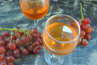 Üzümler ve bir bardak kırmızı şarap beyaz bir masada bir şişe