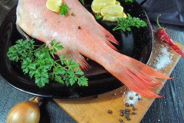 Ahşap arka planda baharatlı ve otlu çiğ balık.