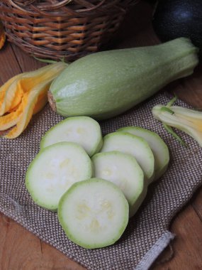 Aşçı ev mutfağında ahşap tahtada kabak kesiyor.