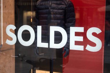 Closeup of discount sign SOLDES in french,  the traduction of  sales in english on the window of fashion store 