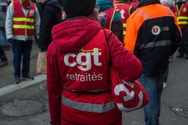 Mulhouse - France - 19 January 2023 - Portrait on back view of old woman protesting in the street with a red jacket with text in french : CGT retraites, in english, CGT pensioner 