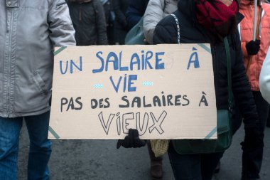 people protesting in the street with pacard in french : salaire a vie pas des salaires a vieux, in english,  a salary for life, not salaries for old