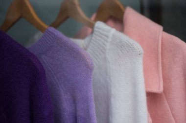 Closeup of colorful woolen pullover on hangers in a fashion store showroom