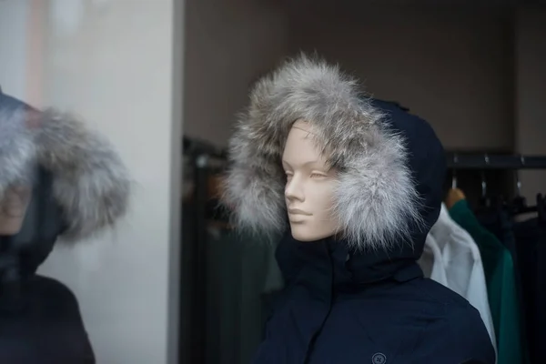 Closeup of winter coat with hood on mannequin in a fashion store showroom