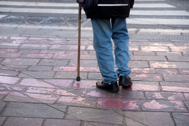 Closeup of old man standing in the street with stick 