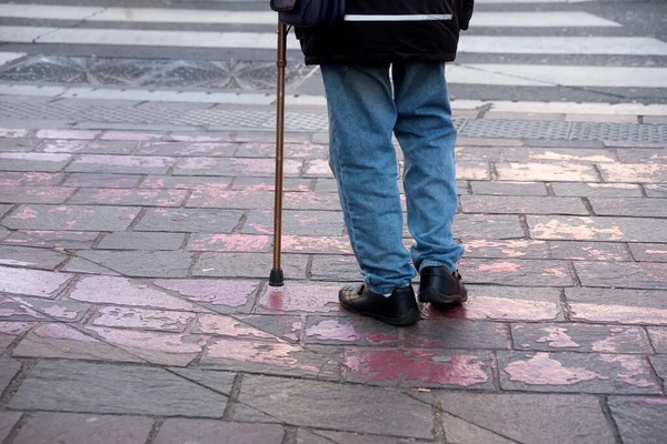 Closeup of old man standing in the street with stick 