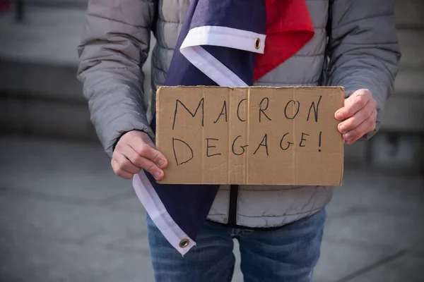 Closeup of man protesting in the street with placard in french : Macron degage, in english, macron resignation