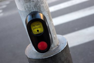 closeup of pedestrian button with text in french attendez pistons, raduction in english wait pedestrians