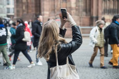 Strazburg - Fransa - 4 Mart 2023 - Sokakta akıllı telefonuyla fotoğraf çeken genç bir kadının portresi