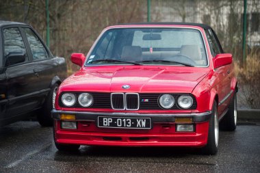 Mulhouse - Fransa - 11 Mart 2023 - Caddeye park edilmiş kırmızı BMW M3 model arabanın ön görüntüsü 