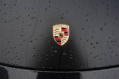 Mulhouse - Fransa - 11 Mart 2023 - Sokakta park etmiş siyah bir arabanın üzerindeki Porsche logosuna yağmur damlalarının yakın çekimi  
