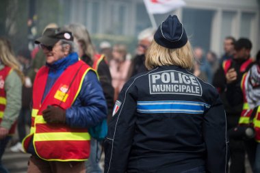 Mulhouse - Fransa - 6 Nisan 2023 - Sokakta duran Fransız polisinin arka plandaki portresi