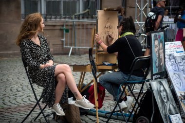 Strasbourg - Fransa - 22 Temmuz 2023 - Sokaktaki bir ressama poz veren turist portresi