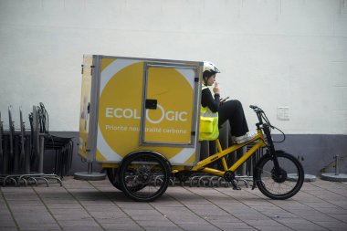 Strasbourg - Fransa - 5 Ağustos 2023 - Sokakta duran postacı kadın ve elektrikli bisikletin portresi 