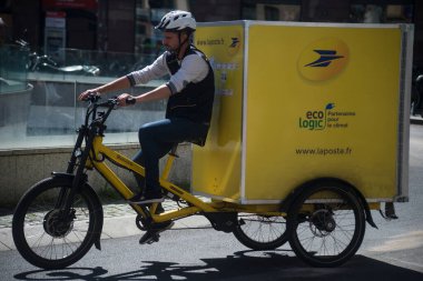 Sokakta duran postacı ve elektrikli bisikletin portresi. 
