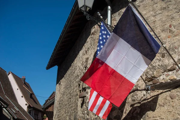 Closeup of french flag and american flag on medieval house in the street