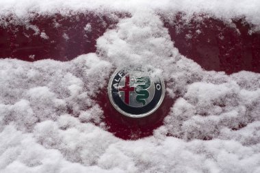Mulhouse - Fransa - 10 Ocak 2024 - Karla kaplı caddeye park etmiş Alfa Romeo logosunun yakın çekimi