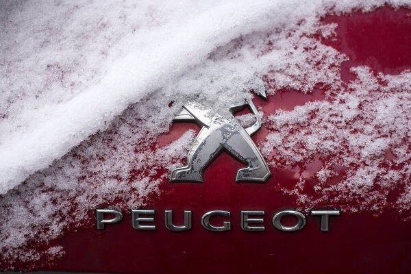 Мюлуз - Франция - 19 января 2024 года - Размещение логотипа Peugeot, покрытого снегом, на красном автомобиле, припаркованном на улице