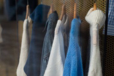 Kadın moda mağazasındaki askılarda asılı renkli yün kazakların yakın çekimi.