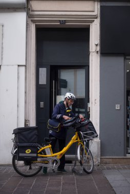 Mulhouse - Fransa - 14 Nisan 2024 - Sokakta bisikletinin yanında duran postacının portresi