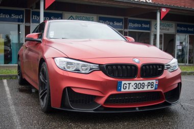 Mulhouse - Fransa - 4 Haziran 2024 - Yağmurlu bir günde sokağa park edilmiş kırmızı BMW M4 'ün ön görüntüsü