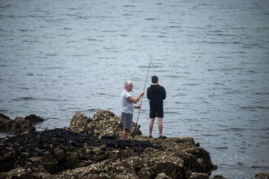 Concarneau - Fransa - 10 Temmuz 2024 - körfezdeki kayalıklarda iki balıkçı görülüyor