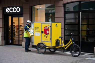 Strasbourg - Fransa - 20 Ekim 2024 - Sokakta duran postacı ve elektrikli bisiklet portresi