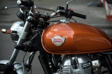 Basel - İsviçre, 24 Mart 2025 - Caddeye park edilmiş turuncu motosiklet tankının Royal Enfield logosu 