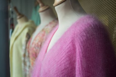 Kadın moda mağazasındaki askılarda asılı renkli yün kazakların yakın çekimi.