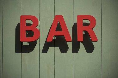 Caddedeki duvardaki bar tabelasının yakınına.