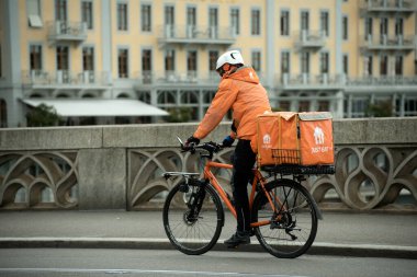 Basel - İsviçre - 20 Mayıs 2025 - sokakta bisikletle yemek yiyen teslimatçının portresi