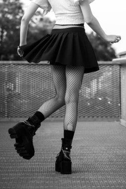 Sokakta duran seksi çoraplar ve siyah çizmeler giyen gotik kızın bacakları.