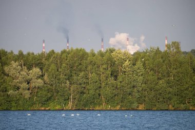 Endüstriyel çelik fabrikası, demir işi. Metalürjik bitki. Çelik fabrikası. Avrupa 'da ağır sanayi. Bacalardan gelen hava kirliliği. Mavi Göl 'ün arka planında demir işçiliği. Doğa ve endüstri.