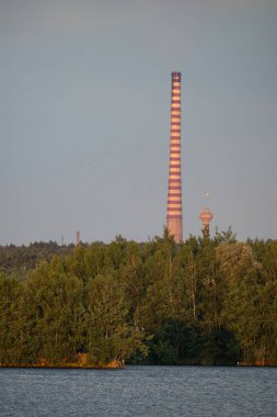 Endüstriyel çelik fabrikası, demir işi. Metalürjik bitki. Çelik fabrikası. Avrupa 'da ağır sanayi. Bacalardan gelen hava kirliliği. Mavi Göl 'ün arka planında demir işçiliği. Doğa ve endüstri.