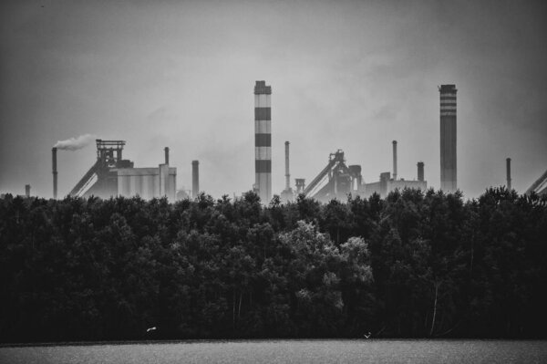 Industrial steel factory, iron works. Metallurgical plant. steelworks. Heavy industry in Europe. Air pollution from chimneys. Ironworks on a background of blue lake. Nature and industry.