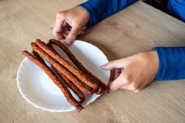Kadın elinde yemek tutuyordu. Kız bir tabakta kabanos sosisi tutuyor. Elinde sosislerle..