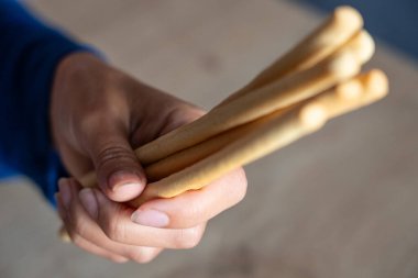 Kadın elinde yemek tutuyordu. Kız Grissini 'yi elinde tutuyor. İtalyan Grissini tutuyor.