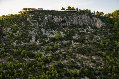Zakynthos 'taki Damianos Mağarası günbatımı çam ağaçları, zeytin ağaçları ve Agalas perspektifinden Akdeniz batımına bakan bir Yunan adasında deniz manzarası. Yunanistan 'ın Zakynthos kentindeki yeşil alanlar ve ormanlar. 