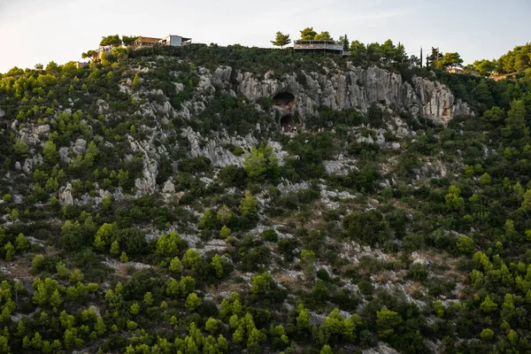 Zakynthos 'taki Damianos Mağarası günbatımı çam ağaçları, zeytin ağaçları ve Agalas perspektifinden Akdeniz batımına bakan bir Yunan adasında deniz manzarası. Yunanistan 'ın Zakynthos kentindeki yeşil alanlar ve ormanlar. 