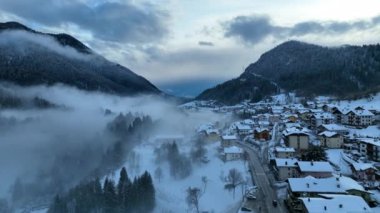 İtalyan Dolomitler 'deki Sisli Şehir' in insansız hava aracı görüntüsü. Alplerdeki İtalyan dağ kasabası Berguzzo. Dolomites Trentino 'daki Adamello Brenta Parkı. İtalyan dağlarında küçük bir kasabada bulutlu bir kış günü. Kışın sisli dağlar.