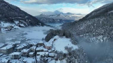 İtalyan Dolomitler 'deki Sisli Şehir' in insansız hava aracı görüntüsü. Alplerdeki İtalyan dağ kasabası Berguzzo. Dolomites Trentino 'daki Adamello Brenta Parkı. İtalyan dağlarında küçük bir kasabada bulutlu bir kış günü. Kışın sisli dağlar.