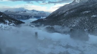 İtalyan Dolomitler 'deki Sisli Şehir' in insansız hava aracı görüntüsü. Alplerdeki İtalyan dağ kasabası Berguzzo. Dolomites Trentino 'daki Adamello Brenta Parkı. İtalyan dağlarında küçük bir kasabada bulutlu bir kış günü. Kışın sisli dağlar.