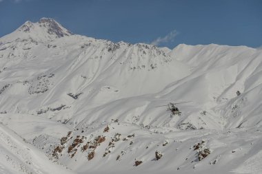 Dağlarda bir helikopter var. Kafkasya 'da serbest helikopter sörfü. Kışın serbest snowboard sporu. Helikopter paraşütü. Kar bordasında toz içinde gezmek. Kafkasya dağlarında serbest dolaşmak. 