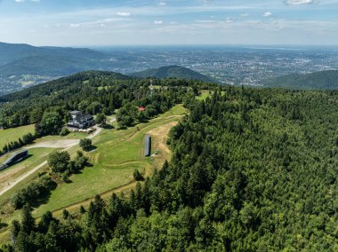 Beskids, Bielsko Biala, Magurka Wilkowicka 'daki yeşil ormanların çarpıcı hava aracı görüntüsü. Magurka Wilkowicka 'da bir barınak. Tepelerin manzarası yemyeşil yeşilliğin güzelliğini ve huzurunu yansıtır.. 