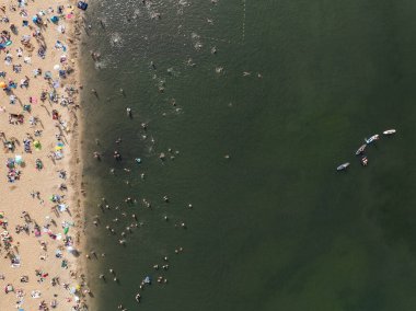 Summer Lake Sahili 'nin hava aracı görüntüsü. Yeşil gölde güneşli bir yaz tatili. Güneşlenmek ve sahilde dinlenmek. Polonya 'daki gölde tatil. İnsanlar göl sahilinde güneşleniyor..